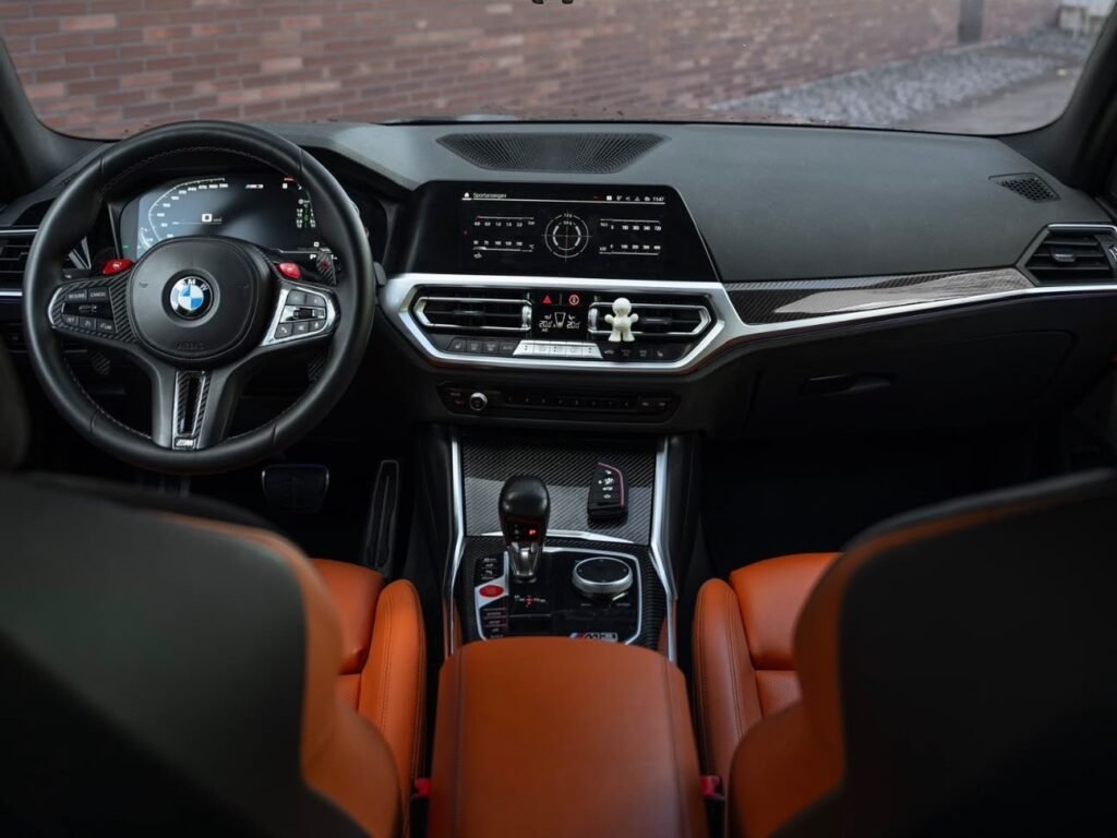 BMW M3 Competition Innenraum mit orangen M Sportsitzen und digitalem Cockpit – Sportwagen mieten Schaffhausen